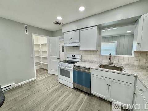 A kitchen with white cabinets and a blue backsplash.