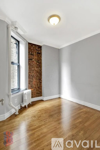 A room with wooden floors and a brick wall.
