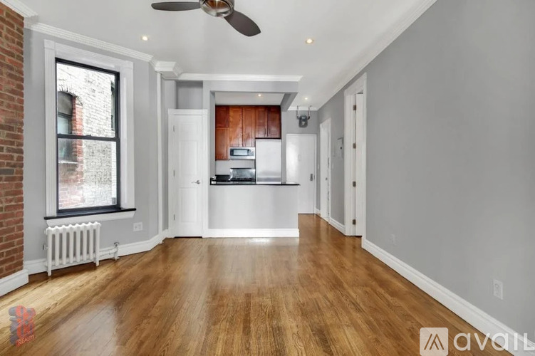A spacious kitchen with wooden floors and white walls.