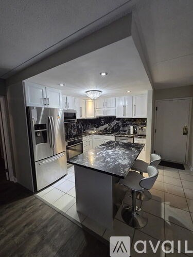 A modern kitchen with a marble countertop and stainless steel appliances.