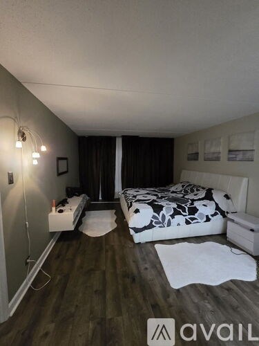 A bedroom with a bed, nightstand, and a wall-mounted light fixture.