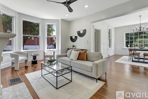 A living room with a glass coffee table and a fan on the ceiling.