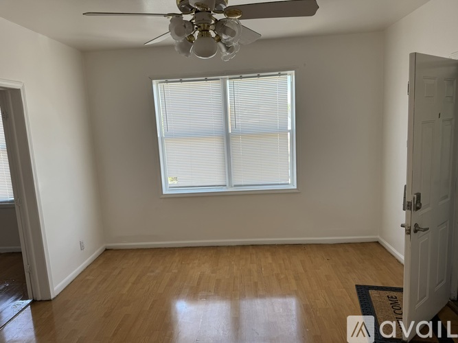 A room with a ceiling fan and a window with blinds.