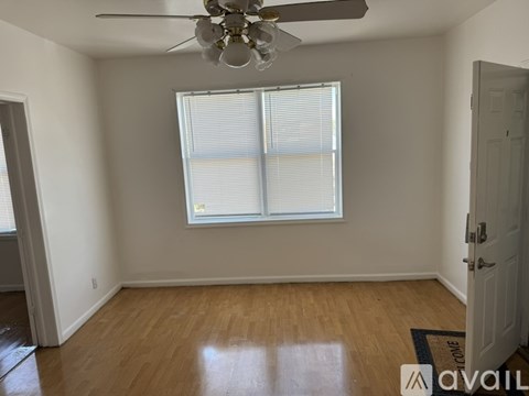 A room with a ceiling fan and a window with blinds.