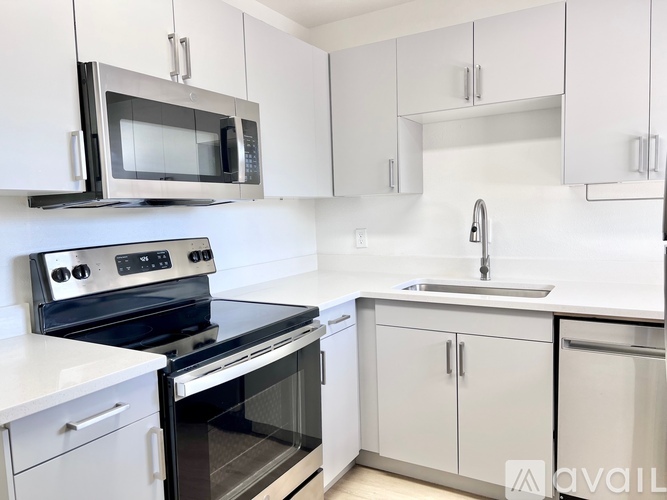 A kitchen with white cabinets and a black microwave above the stove.