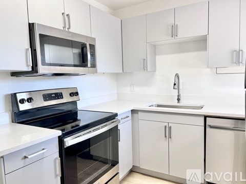 A kitchen with white cabinets and a black microwave above the stove.