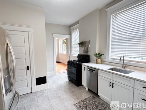 A kitchen with white cabinets and a black dishwasher.