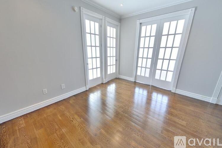A room with wooden floors and white walls with windows.
