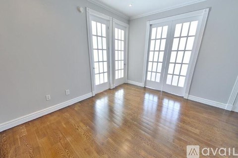 A room with wooden floors and white walls with windows.