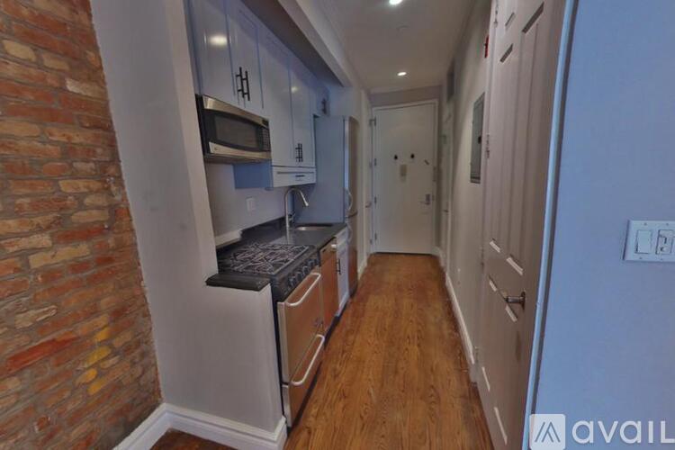 A kitchen with a brick wall and wooden floors.