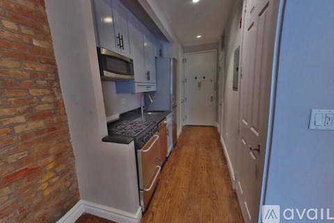 A kitchen with a brick wall and wooden floors.