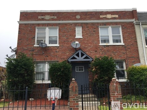 A brick house with a black door and a black fence.