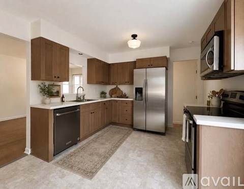 A kitchen with wooden cabinets and a stainless steel refrigerator.