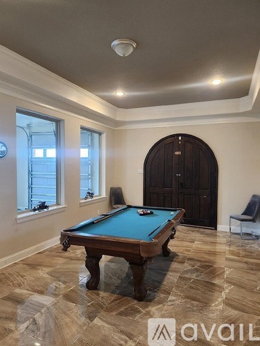 A pool table in a room with a large window and a door.