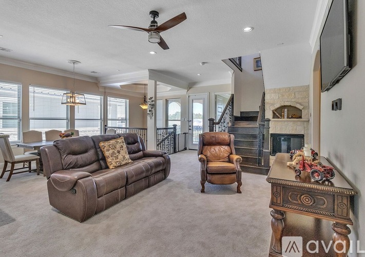 A living room with a brown couch and a fan on the ceiling.