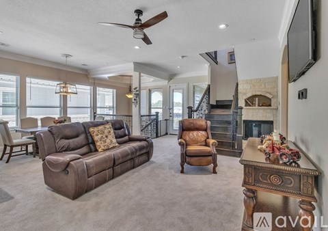 A living room with a brown couch and a fan on the ceiling.