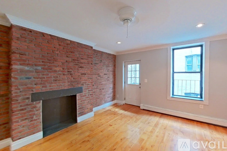 A room with a brick fireplace and wooden floors.