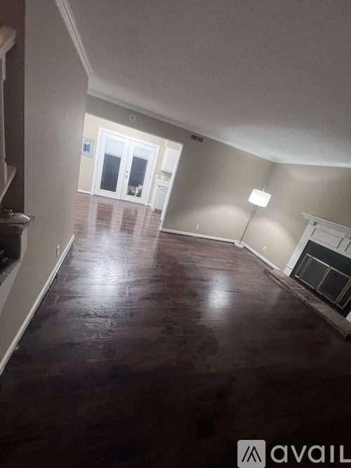 A room with a dark wood floor and a fireplace.