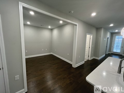 A spacious room with wood flooring and white walls.