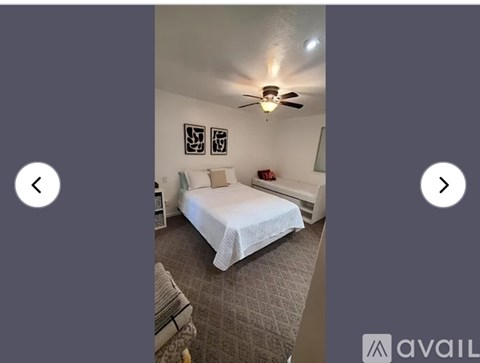 A bedroom with a bed, pillows, a ceiling fan, and pictures on the wall.