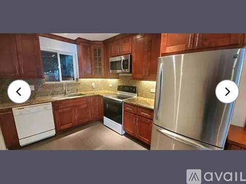 A kitchen with wooden cabinets and a stainless steel refrigerator.