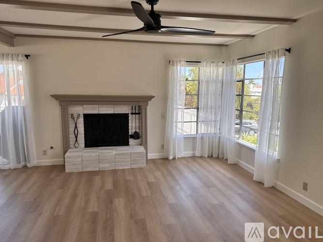 A living room with a fireplace and a ceiling fan.
