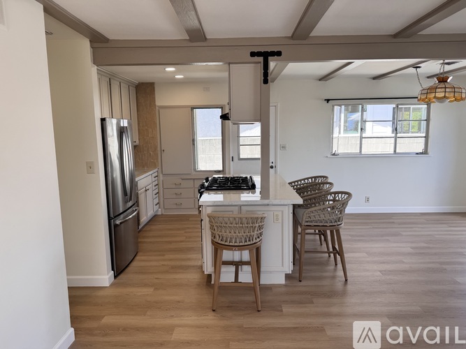 A kitchen with a refrigerator, sink, and dining table with chairs.
