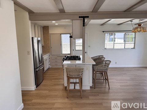 A kitchen with a refrigerator, sink, and dining table with chairs.