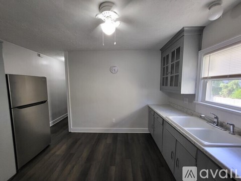 A kitchen with a stainless steel refrigerator and wooden floors.