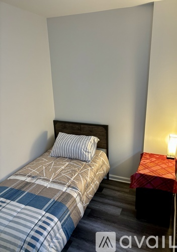 A bedroom with a bed and a small table with a lamp.