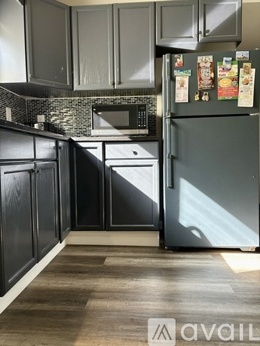 A kitchen with black cabinets and a grey fridge.
