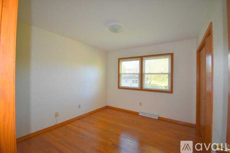 A room with wooden floors and a window with a view of a building.