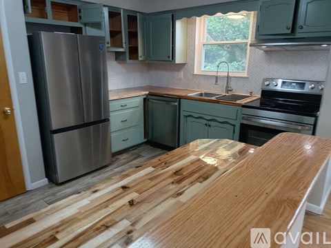 A kitchen with a wooden table and a stainless steel refrigerator.