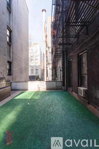 A narrow alley with a green floor and buildings on either side.