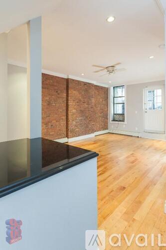 A room with wooden floors and a brick wall.