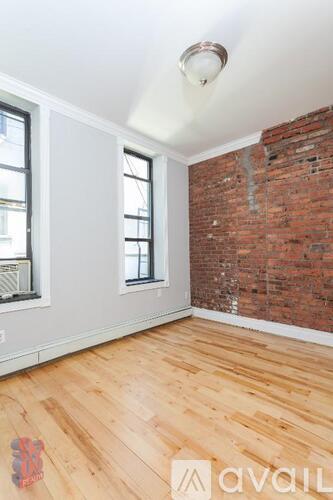 A room with wooden floors and a brick wall.