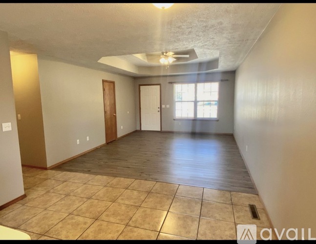 A spacious room with tile flooring and a ceiling fan.