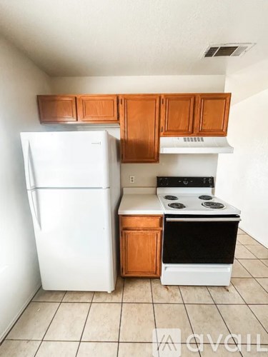 A kitchen with a white fridge and a white stove with a wooden cabinet above it.