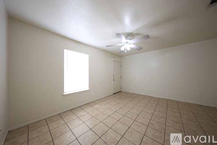 A spacious room with a ceiling fan and tiled flooring.