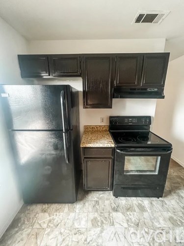 A black fridge and oven in a kitchen with black cabinets.