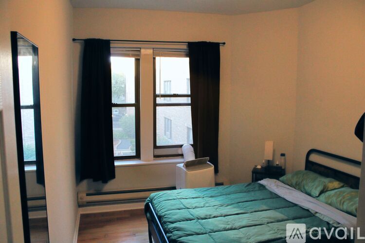 A bedroom with a bed, nightstand, and window with curtains.