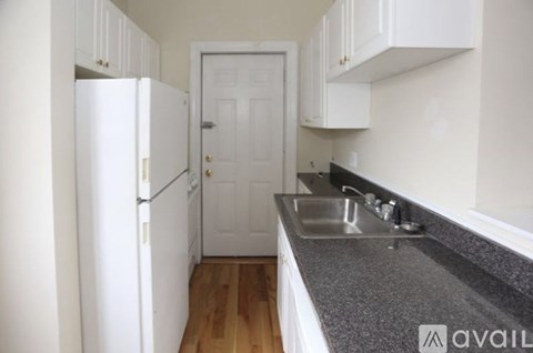 A kitchen with a white fridge and a white door.