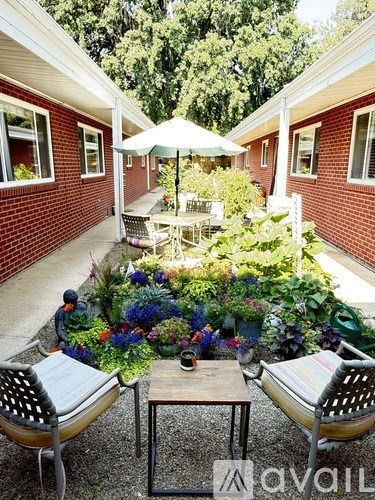A patio with a table and chairs surrounded by a garden.