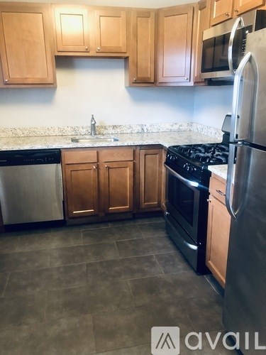 A kitchen with wooden cabinets and a black fridge.