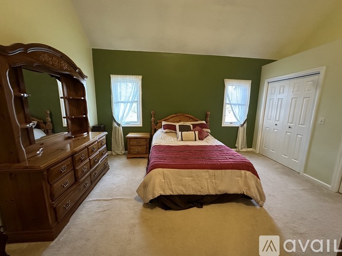 A bedroom with a bed, dresser, and mirror.