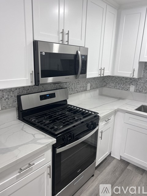 A kitchen with white cabinets and a black stove top oven.