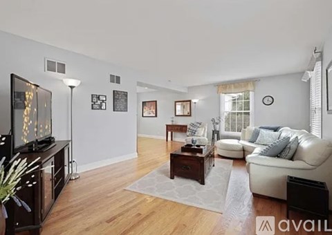 A living room with a white couch and a wooden floor.