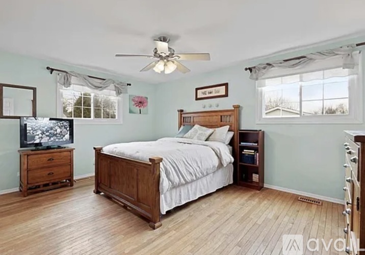 A bedroom with a bed, dresser, and television.