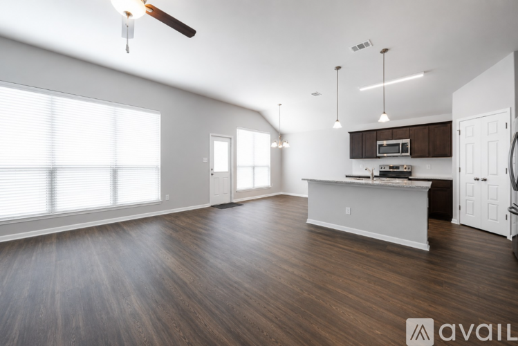 A spacious living room with a kitchenette and hardwood floors.