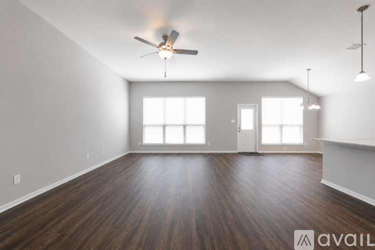 A spacious room with wooden floors and a ceiling fan.